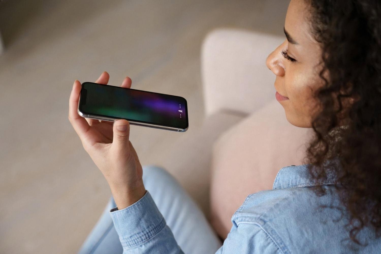 Young woman using an AI voice assistant on her smartphone while studying at home