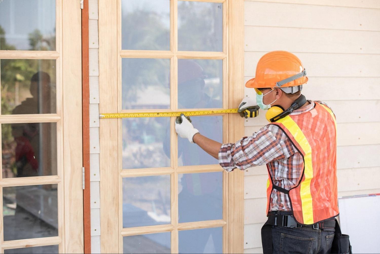 Handyman in a hard hat measuring a wooden door frame during a Dubai home inspection